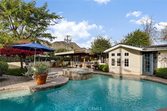 pool with a patio area and an in ground hot tub