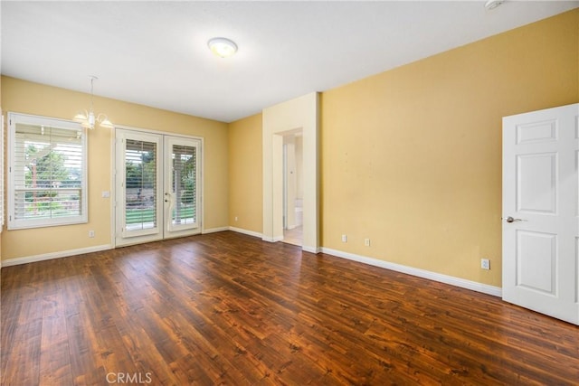 unfurnished room with a notable chandelier, french doors, dark wood finished floors, and baseboards