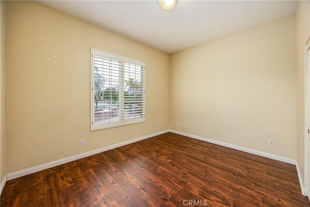 empty room featuring dark wood-type flooring and baseboards