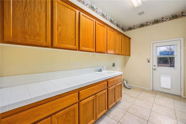 laundry area featuring cabinet space, light tile patterned floors, visible vents, washer hookup, and a sink