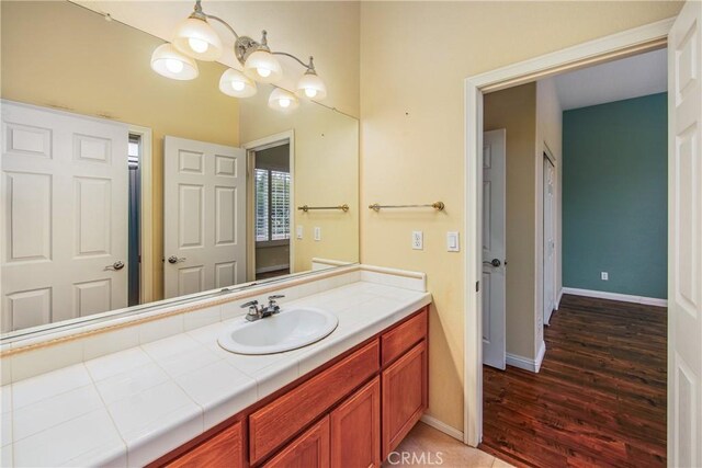 bathroom featuring vanity, baseboards, and wood finished floors