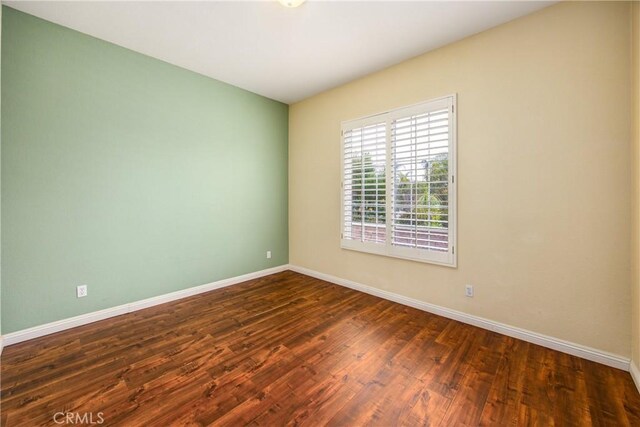 spare room with dark wood finished floors and baseboards