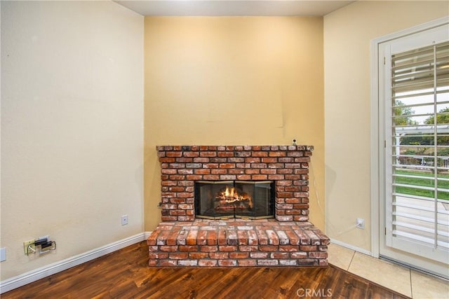 interior details featuring a brick fireplace, baseboards, and wood finished floors