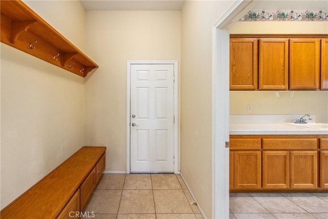 mudroom with light tile patterned flooring, a sink, and baseboards