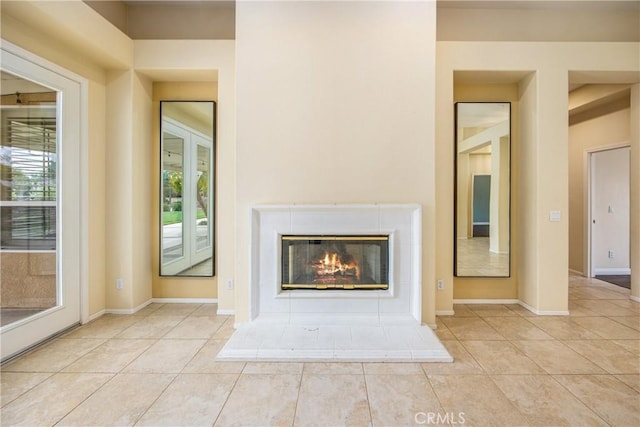 unfurnished living room featuring tile patterned flooring, baseboards, and a glass covered fireplace