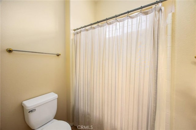 bathroom with a shower with shower curtain and toilet