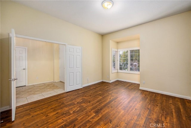 unfurnished room with baseboards and hardwood / wood-style flooring