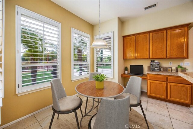 dining space featuring light tile patterned floors, a healthy amount of sunlight, visible vents, and built in study area