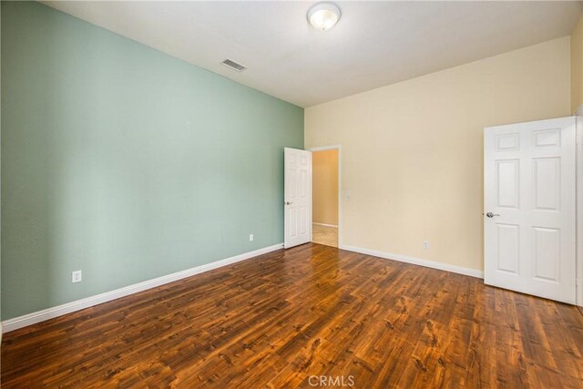 unfurnished room featuring visible vents, baseboards, and wood finished floors