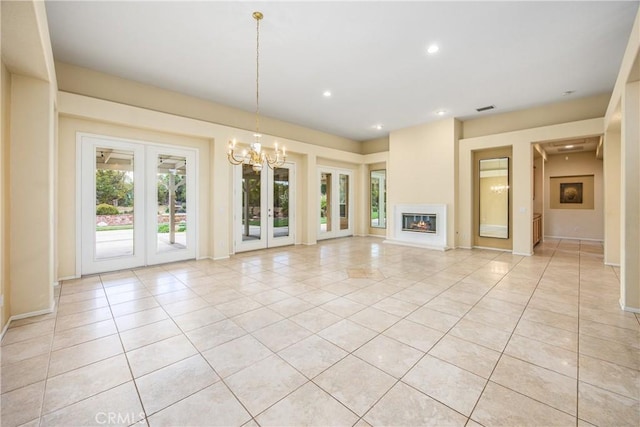 unfurnished living room with light tile patterned floors, recessed lighting, a glass covered fireplace, and french doors