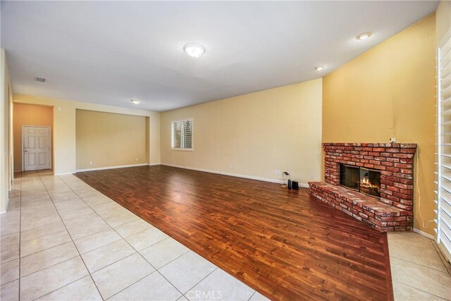 unfurnished living room featuring light wood-type flooring, a fireplace, and baseboards