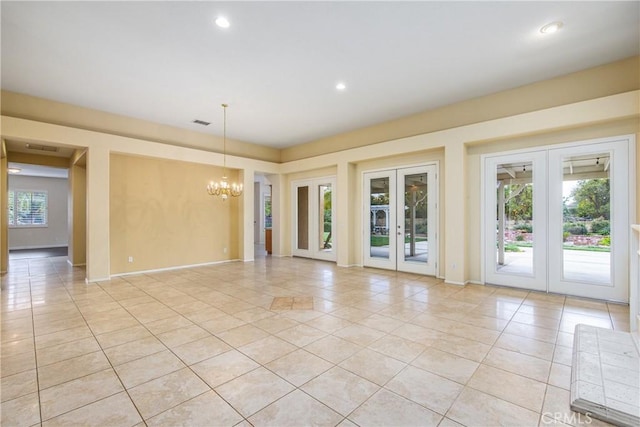 empty room with plenty of natural light, light tile patterned flooring, a notable chandelier, and french doors