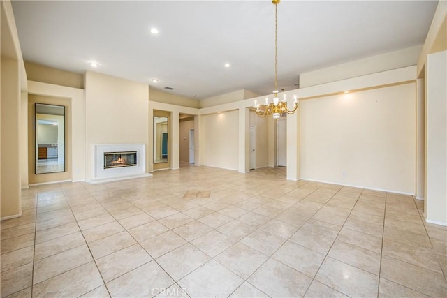 unfurnished living room with a notable chandelier, light tile patterned floors, recessed lighting, a glass covered fireplace, and baseboards