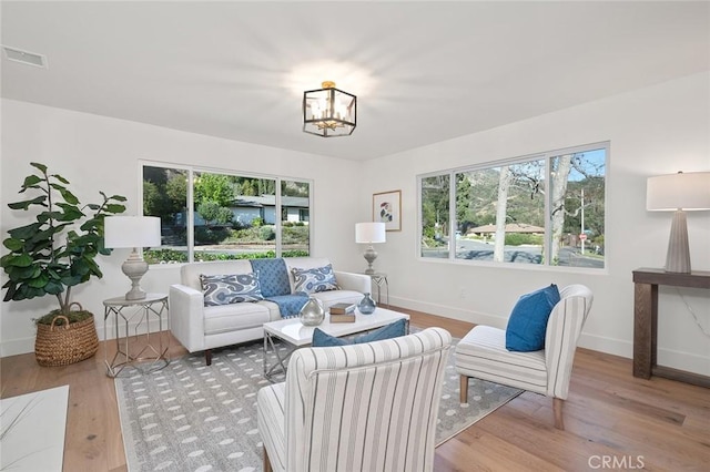 living area featuring baseboards, a chandelier, and wood finished floors