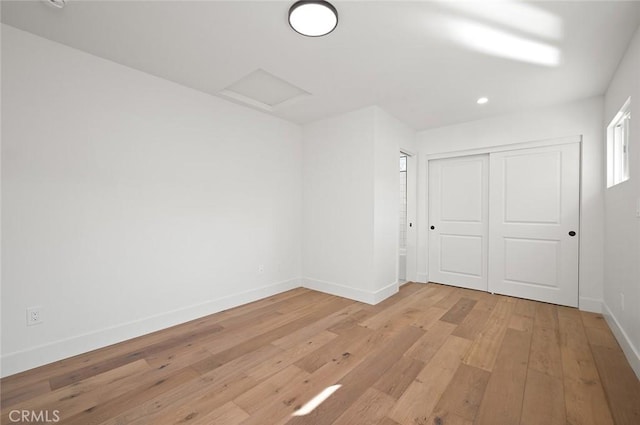 unfurnished bedroom featuring light wood-style flooring, baseboards, attic access, a closet, and recessed lighting