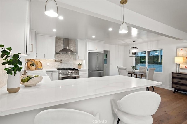 kitchen with high end appliances, wall chimney exhaust hood, a sink, dark wood-type flooring, and decorative backsplash