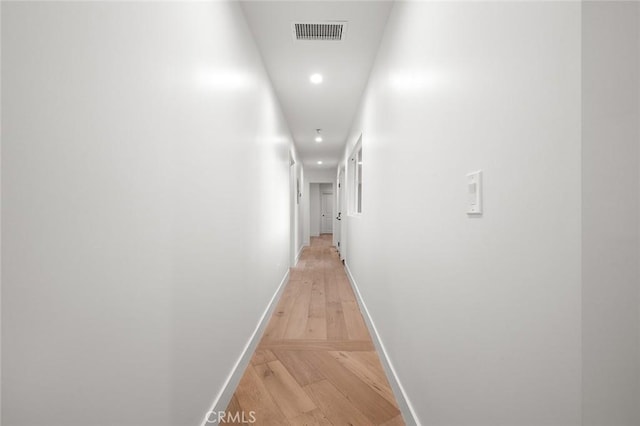 corridor featuring baseboards, recessed lighting, and light wood finished floors
