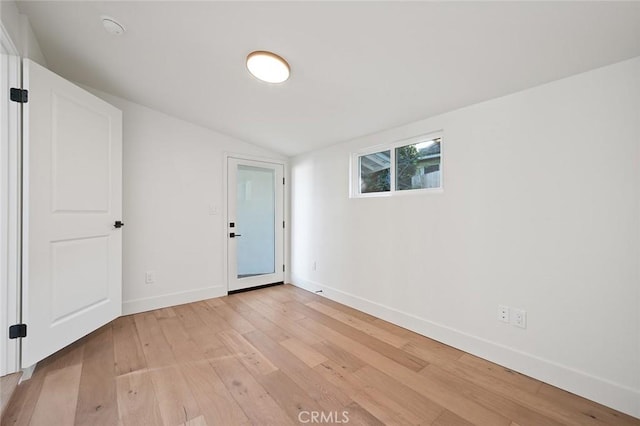 unfurnished room with light wood-style flooring, vaulted ceiling, and baseboards