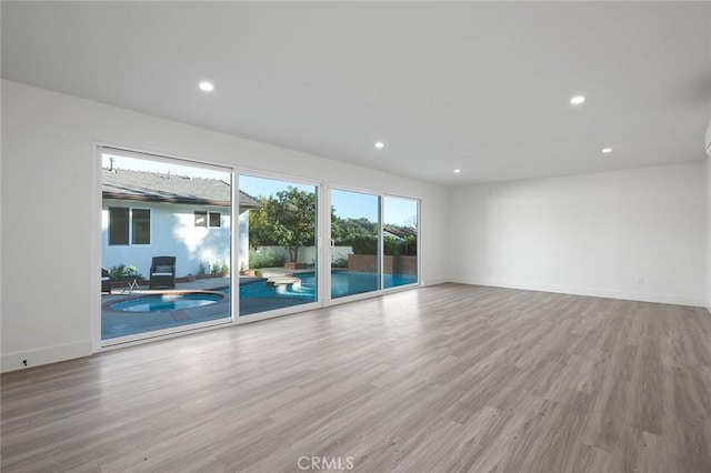 spare room featuring wood finished floors, recessed lighting, and baseboards