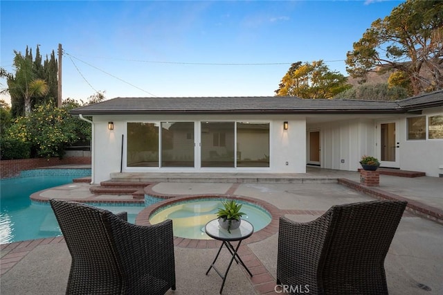 back of property featuring a patio area, stucco siding, and a pool with connected hot tub