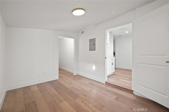 spare room featuring light wood finished floors, electric panel, baseboards, and a smoke detector
