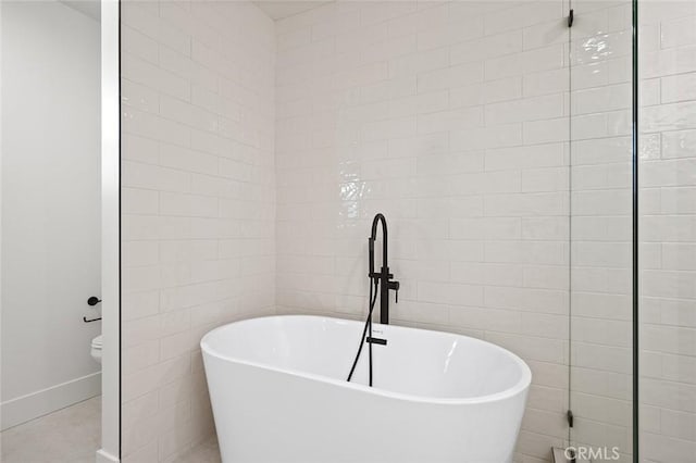 full bathroom with a soaking tub, baseboards, and tile walls