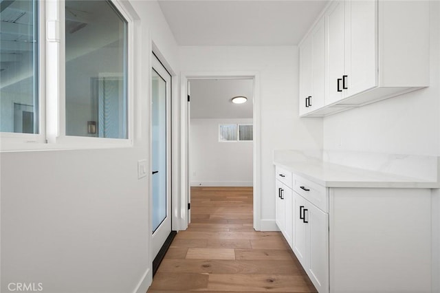 corridor featuring light wood-style flooring and baseboards