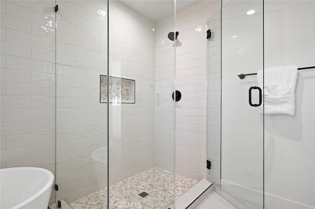 bathroom with a stall shower, a freestanding bath, and recessed lighting