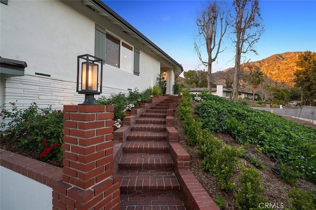 view of side of home with stucco siding and a mountain view