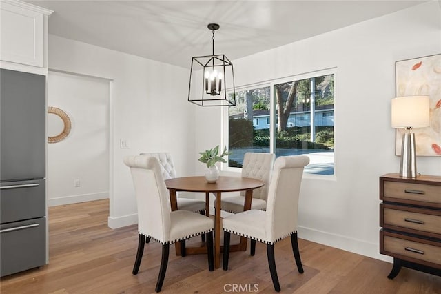 dining space featuring a chandelier, light wood-type flooring, and baseboards
