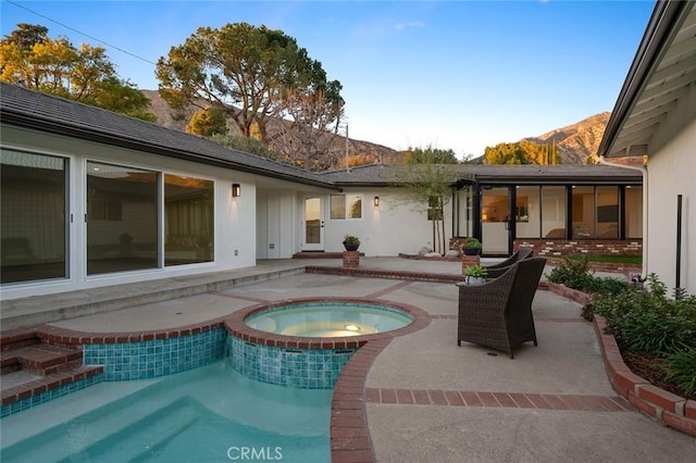 view of swimming pool featuring a patio area, a mountain view, and a pool with connected hot tub