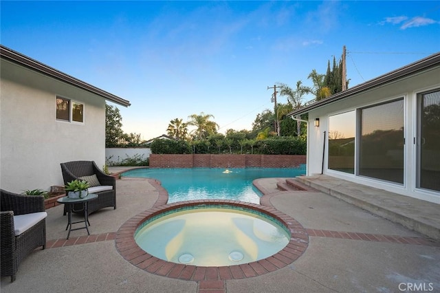 pool at dusk with a patio and a pool with connected hot tub