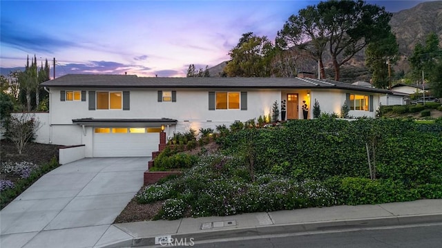 view of front of house featuring stucco siding, concrete driveway, and an attached garage