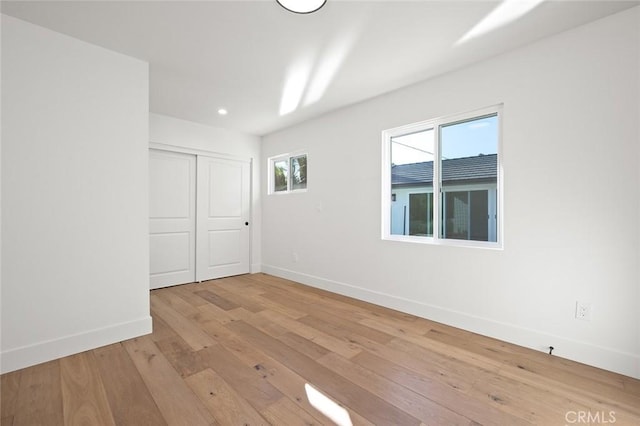 empty room with baseboards, light wood finished floors, and recessed lighting