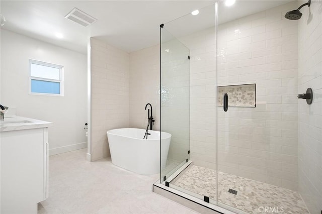 bathroom with a shower stall, a freestanding tub, recessed lighting, baseboards, and vanity