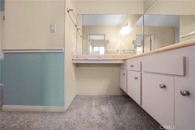 bathroom featuring carpet, vanity, and baseboards