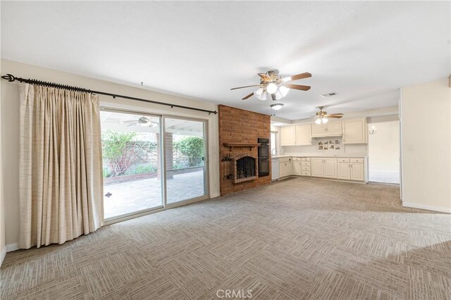 unfurnished living room featuring a brick fireplace, light colored carpet, visible vents, and baseboards