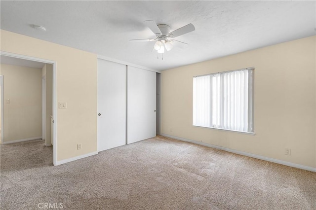 unfurnished bedroom featuring a ceiling fan, carpet, baseboards, and a closet