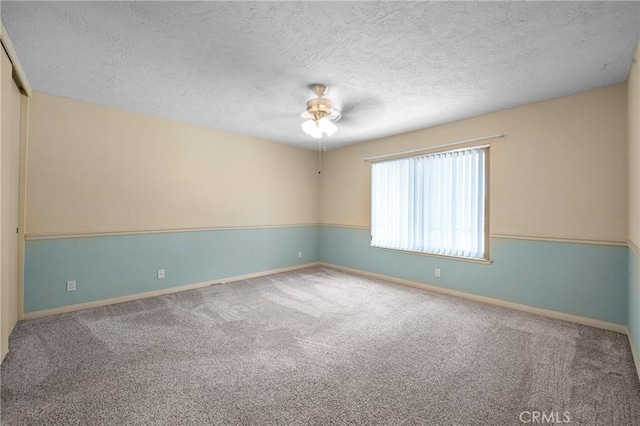 carpeted spare room with a ceiling fan, a textured ceiling, and baseboards