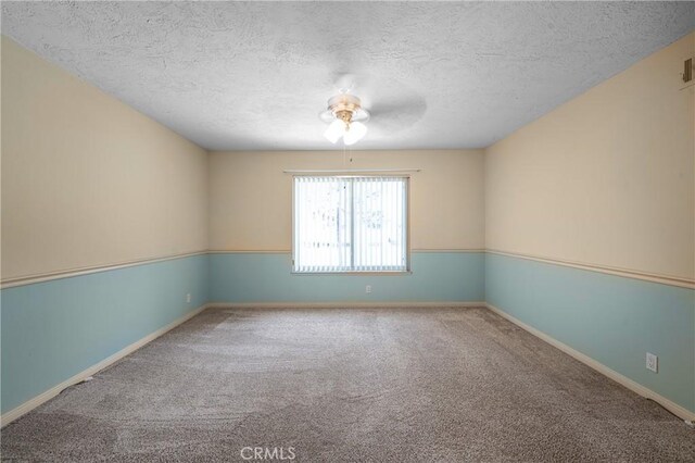 empty room with a textured ceiling, carpet flooring, and baseboards