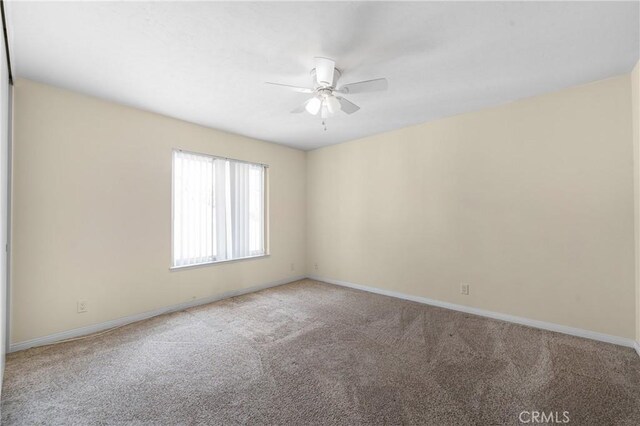 carpeted empty room featuring ceiling fan and baseboards