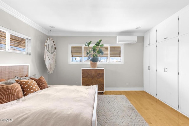 bedroom with a closet, light wood-style flooring, ornamental molding, a wall mounted air conditioner, and baseboards