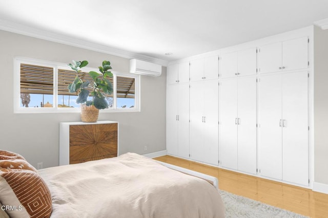 bedroom with light wood finished floors, multiple windows, baseboards, and an AC wall unit