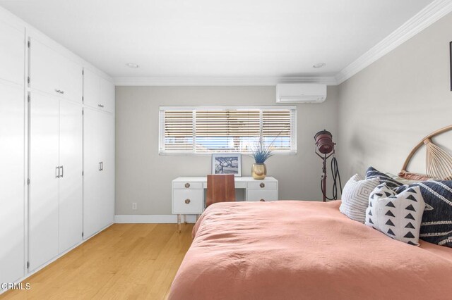 bedroom featuring baseboards, light wood finished floors, a wall mounted AC, and crown molding