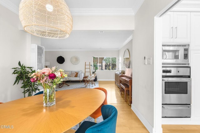 dining room with light wood-type flooring, crown molding, and baseboards