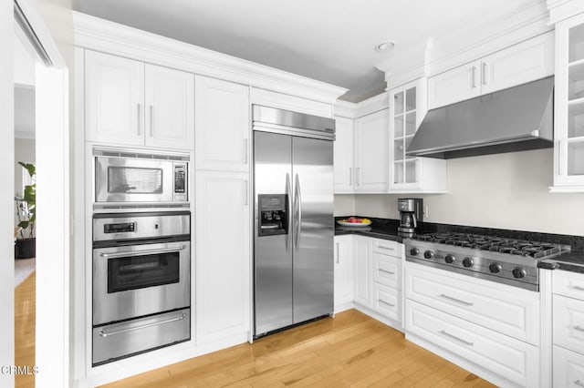 kitchen featuring built in appliances, a warming drawer, white cabinets, and under cabinet range hood