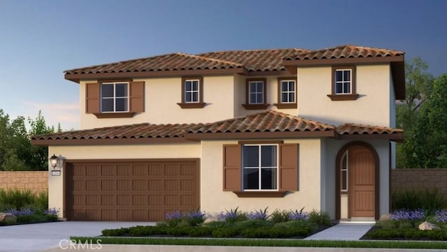 mediterranean / spanish home featuring a garage, concrete driveway, fence, and stucco siding