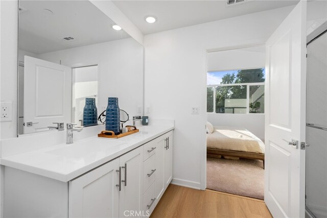 ensuite bathroom featuring connected bathroom, recessed lighting, wood finished floors, vanity, and visible vents