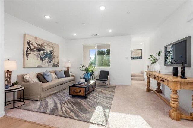 carpeted living area featuring recessed lighting, visible vents, baseboards, and stairs