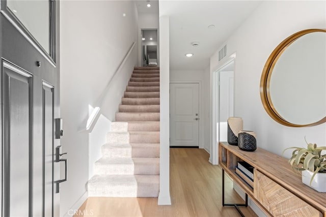 foyer featuring light wood finished floors, stairway, and visible vents